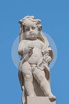 Old statue of a small child in the historical downtown of Dresden, Germany, at blue sky background