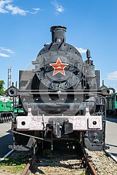 Old steam locomotive beside a railway station platform. Retro train.