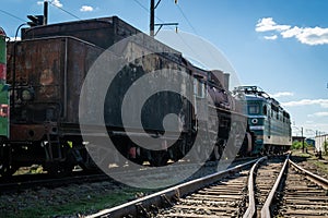 Old steam locomotive beside a railway station platform. Retro train