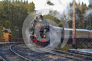 An old steam locomotive with a train arrives at the platform