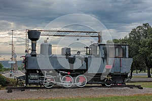Old steam locomotive at train station on cloudy day