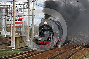 An old steam train in clouds of smoke rides by rail photo