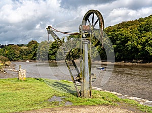 Old steel cargo winch on harbour by tidal River Tamar in Devon