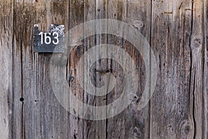 Old steel house number plate 163 on a wood background