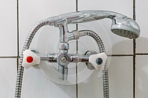 Old steel shower faucet at white vintage tile background