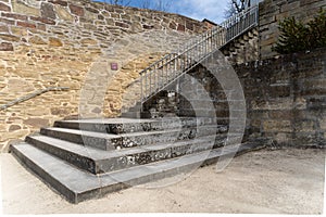 Old steep staircase next to sandstone wall