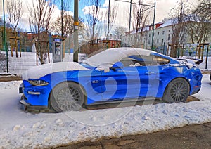 Old blue sport coupe car Ford Mustang parked in snow in Gdansk, March 12th, 2023.