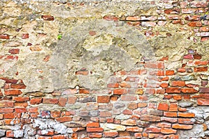 Old stone and brick wall with degraded plaster