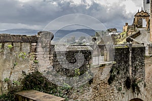 Old stone bridge with its walls full of moss and plants with a metal railing