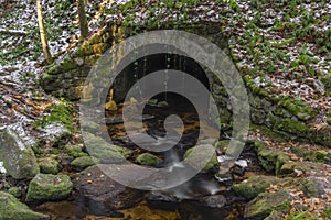 Old stone bridge over Konsky creek in winter day in Sumava national park