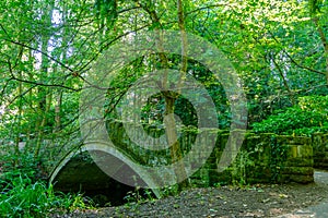 Old stone bridge over stream in Desmond Dene park, Newcastle, UK