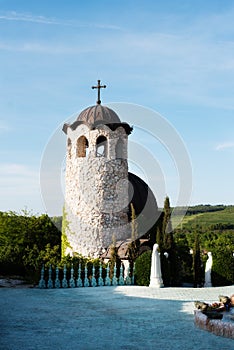 Old stone chapel in the garden of fabulous ancient castle. Alley in beautiful garden with flowers and trees around. Summer in the