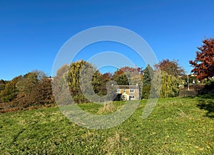 Old stone cottage, with fields and trees, set against a blue sky near, Poplar Road, Shipley, UK