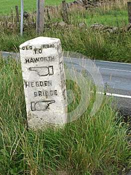 Old stone direction marker on the old road between howarth and hebden bridge with carved fingers indicating the way