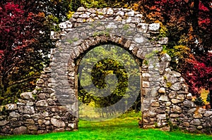 Old stone entrance wall in the garden with colorful foliage