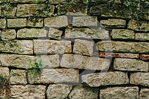 Old stone fence. Cracks between the stones. Moss on the ruined wall