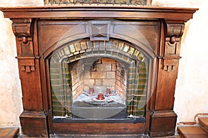 An old stone fireplace with a veneered mahogany facade and three red candles inside