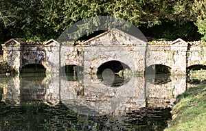 Old stone footbridge reflected in river