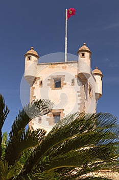 Old stone fortress tower with a flag on the fortress wall of Cadiz.