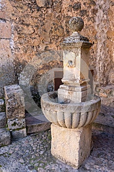 Old stone fountain to give water to passers-by in the street of the medieval village of Pedraza, Segovia.