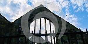 Old stone gable structure in silhouette against blue sky with white clouds