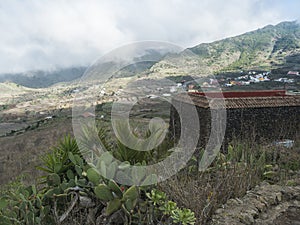 Old stone house at lush green valley with terraced fields and village Las Portelas. Landscape with rocks and hills seen