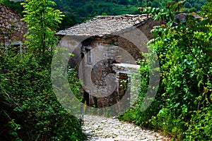 Old stone house by the village stone road. Nature and village concept with old retro stone buildings and roads.