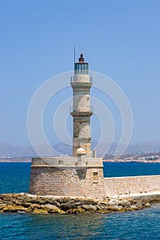 An old stone lighthouse guarding the entrance to a port Chania, Crete, Greece
