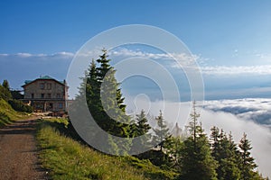 Old stone mountain  cottage  in Jeseniky mountains on a summer foggy morning and  sea of clouds around mountain peak