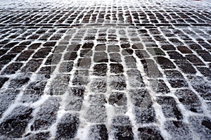 Old stone pavement covered with snow in winter