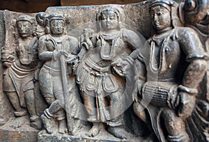 Old stone sculpture with drummer and people listening music. Relief of the 12th century Hoysaleshwara temple in India