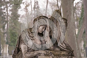 Old stone sculpture of sad woman in grief. Virgin Mary stone statue death concept