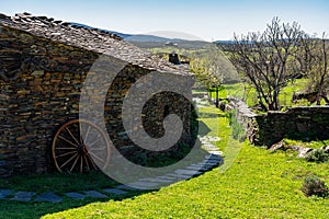 Old stone and slate houses in a green field in the mountains of Guadalajara, Spain.