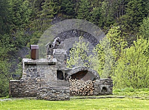 Old stone stove with wood and smokehouse in the mountains