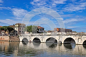 Old stone Tiberius bridge and buildings in Rimini photo