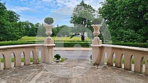 Old stone vases with green bushes at the exit from the terrace to the park