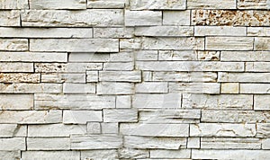 Old stone wall cladding made of horizontal white bricks with brown spots, of natural rock stacked