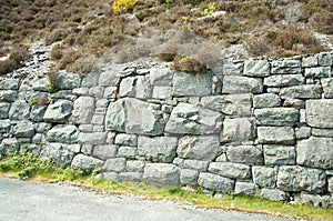 Old stone wall by a roadside.