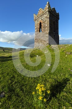 An old stone Watch tower over looking Dingle Bay Co. Kerry Ireland as a fishing boat heads out to sea.