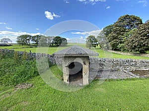 Old stone water cover, with fields and trees, in the distance in, Timble, Otley, UK photo