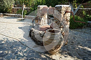 An old stone well for water with a bucket and jugs is located near the Epar. Od. Lardou-Lindou road in Lardos, Rhodes, Greece