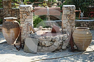 An old stone well for water with a bucket and jugs is located near the Epar. Od. Lardou-Lindou road in Lardos, Rhodes, Greece