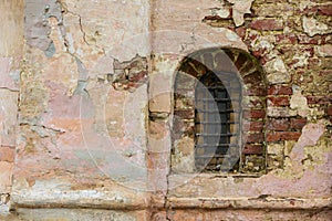Old stone window old Russian style. Vintage window of a 16th-century Church with peeling bricks in Russia. Bars on an ancient