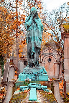 Old stone woman monument in the most famous cemetery of Paris Pere Lachaise, France. Tombs of various famous people