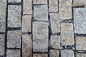 An old stoneblock pavement cobbled with rectangular granite blocks with crushed rock fines between blocks