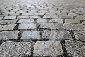 An old stoneblock pavement cobbled with rectangular granite blocks with crushed rock fines between blocks as a background