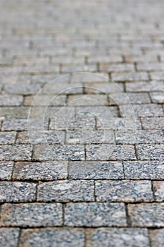 An old stoneblock pavement cobbled with rectangular granite blocks in perspective