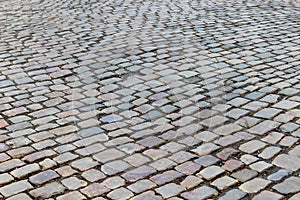 An old stoneblock pavement cobbled with rectangular natural stone blocks with a hole in a place of one stone