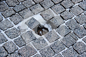 An old stoneblock pavement with a hole in a place of one stone
