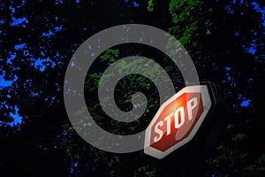 Old stop sign, obeying by european traffic regulations, lit during a dark night, indicating to all vehicles to stop and to yield photo